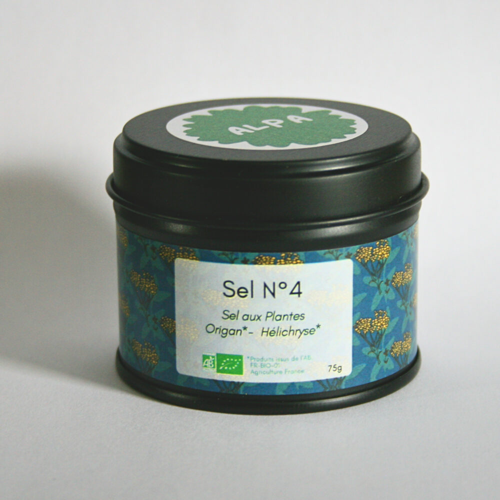 Pot en métal noir fermé contenant le sel aromatique à l’origan et à l’hélichryse, posé sur un fond blanc épuré.